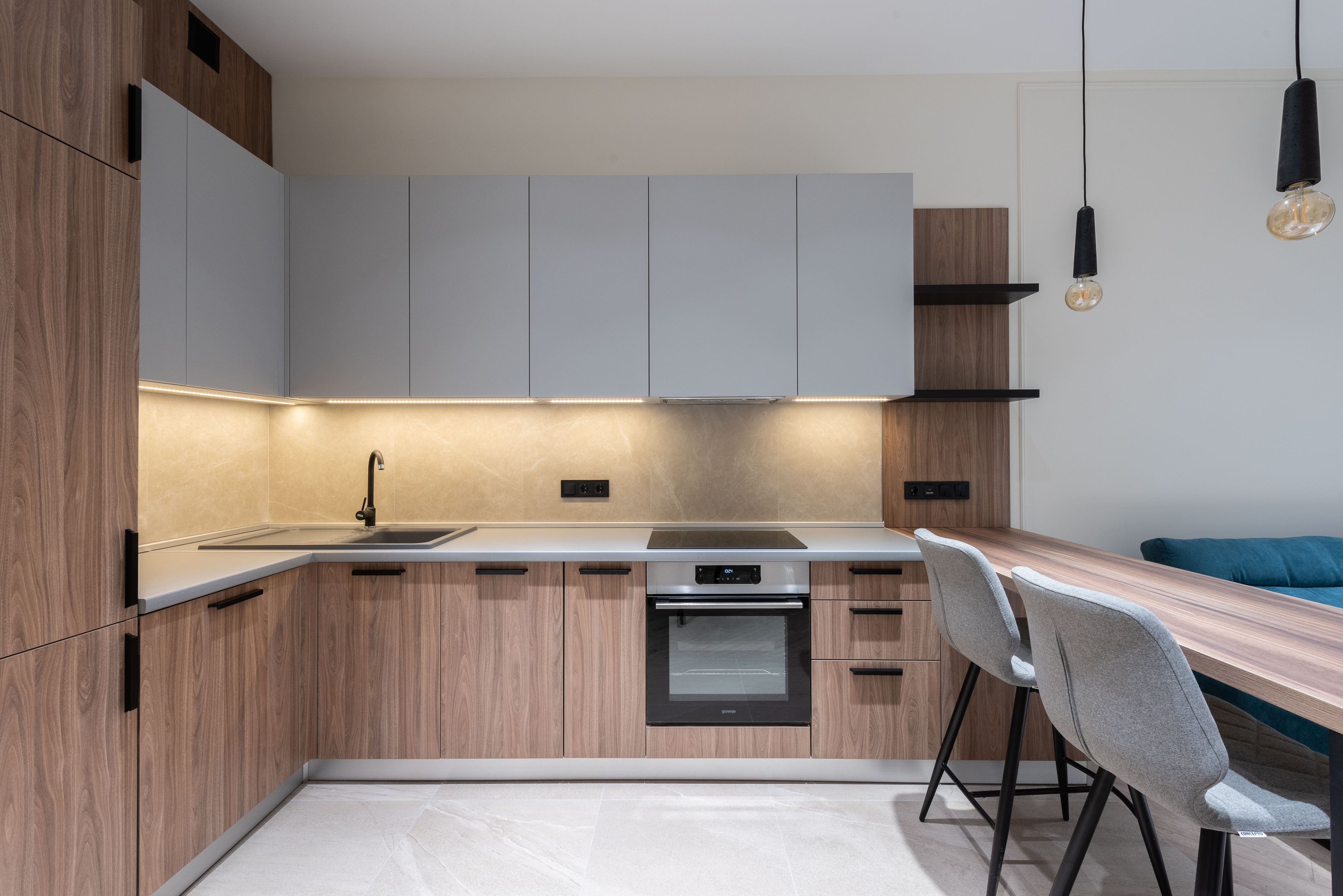 Modular kitchen with wooden cabinetry and built-in oven by Viona Interiors